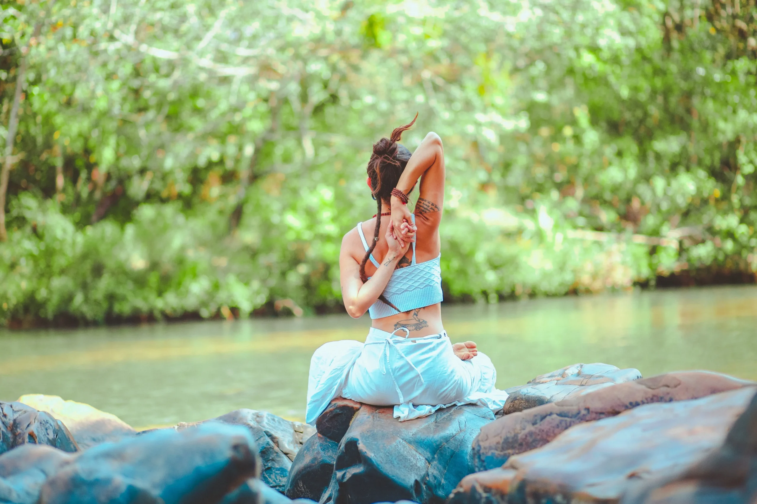 A woman performing a meditative yoga pose in a serene environment, near a waterbody