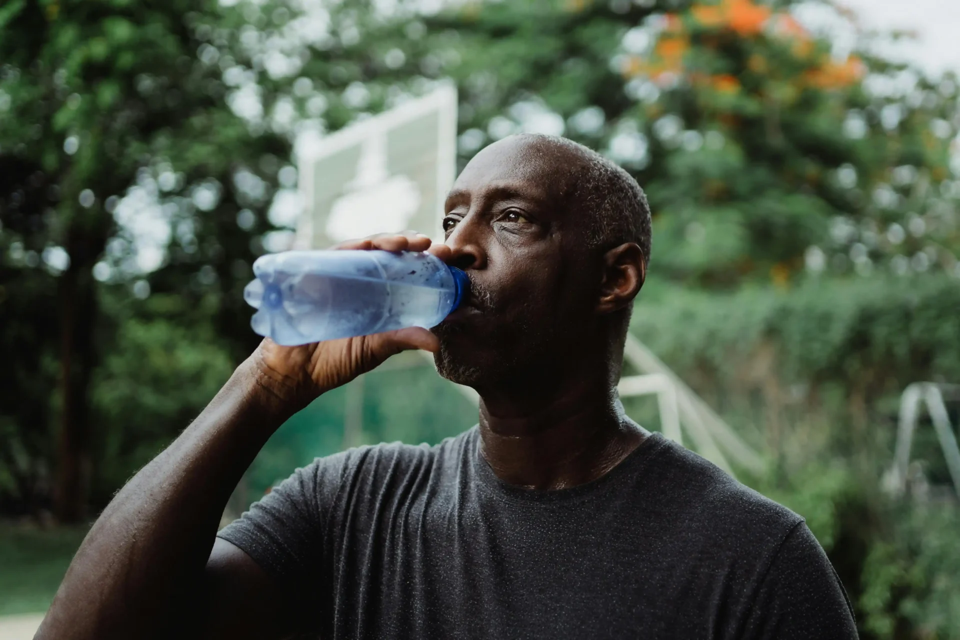 Man in Gray Crew Neck Shirt Drinking Water